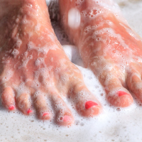 woman's feet standing in soapy water of a shower