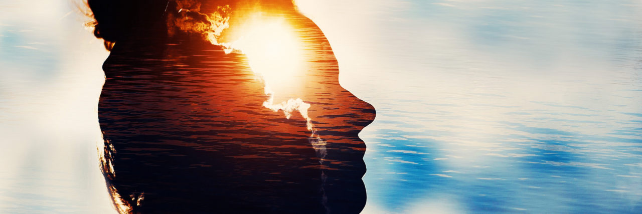 Silhouette of a young woman on a sky background with the sun in her head.
