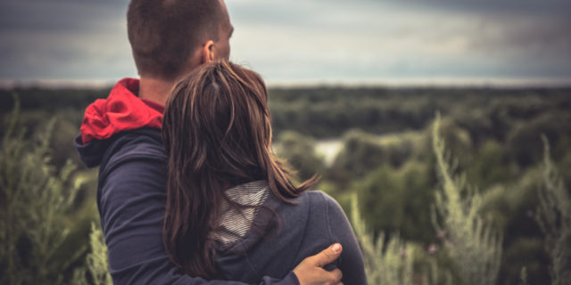 Young couple embracing each other looking out in nature