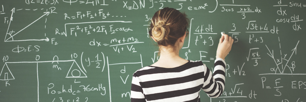 woman writing equations on a chalkboard