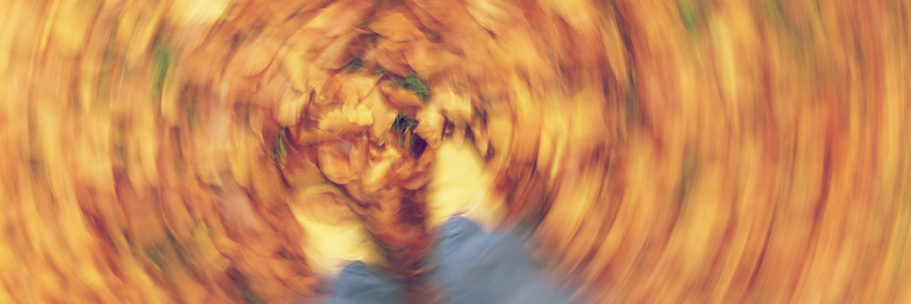 Motion blurred photograph of man or woman's feet walking through golden Fall or Autumn leaves