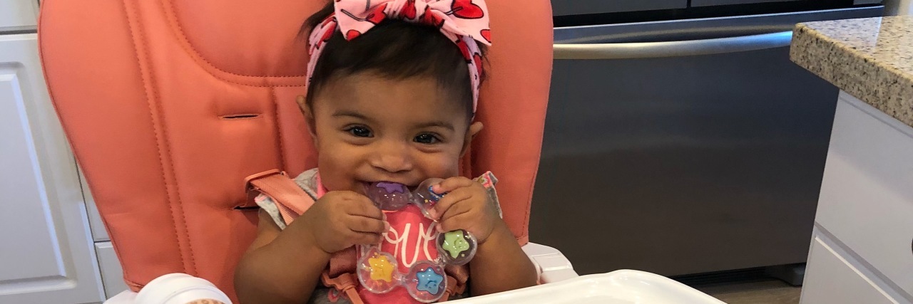 I'm a 'Trained' Heart Mom, But I Panicked When My Baby Choked A baby girl sitting in a high chair with toys.