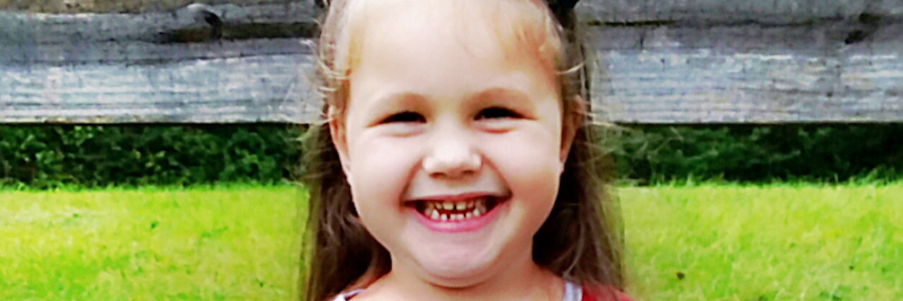 Little girl smiling at camera wearing a shirt that says, "Ain't no mama like the one I got."