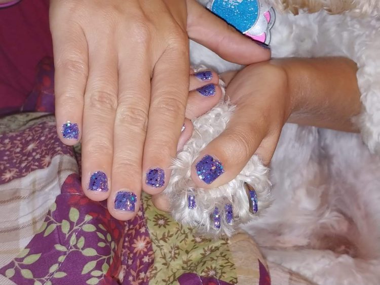 Purple fingernails matching the purple nails of the service dog