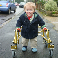 Adorable little boy using yellow walker.