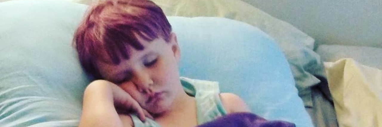 The 'What Ifs' I Worry About for My Daughter With EDS Little girl napping on a soft body pillow with a purple blanket on top.