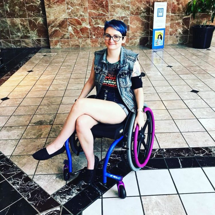 A woman with blue hair in a wheelchair that matches her hair color