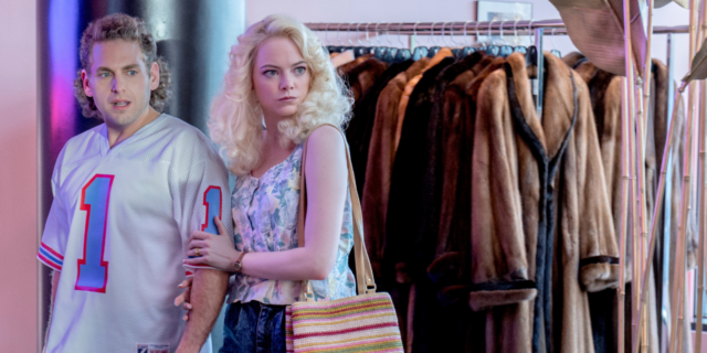 Still of Jonah Hill and Emma Stone in Maniac. Hill is wearing a jersey and Stone has 80s style hair curls.