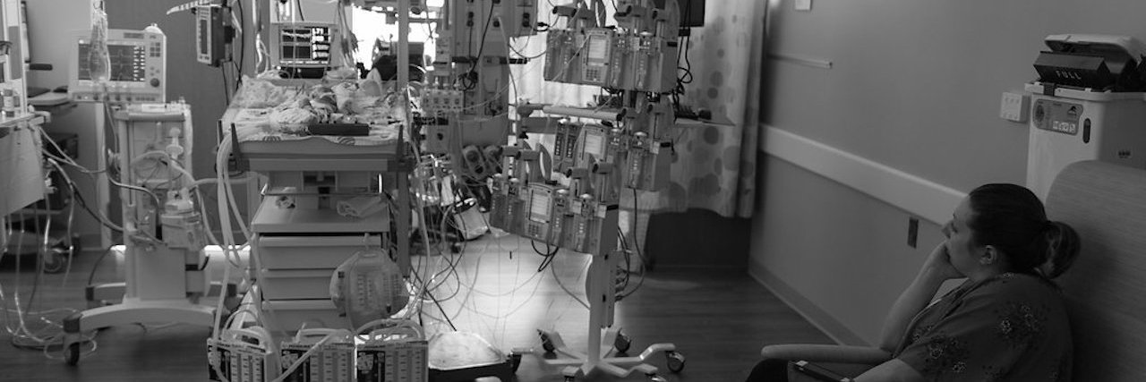 What New Heart Parents Need to Know Black and white image of baby in NICU while mom watched sitting on a chair