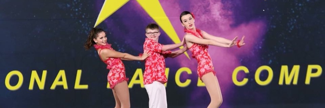 When My Son With Down Syndrome Performed in a Dance Competition Alex in the middle of a "train" on stage dancing