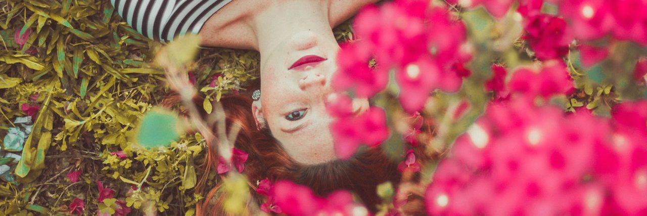 A woman lying in a bed of brightly colored flowers, looking up