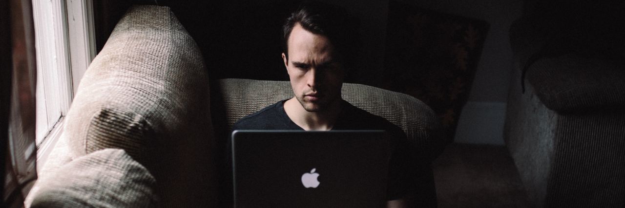 When You're on Information Overload and You Have an Illness to Manage A man sitting in a dark room on his computer.