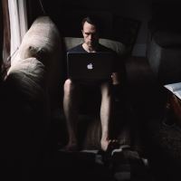 A man sitting in a dark room on his computer.