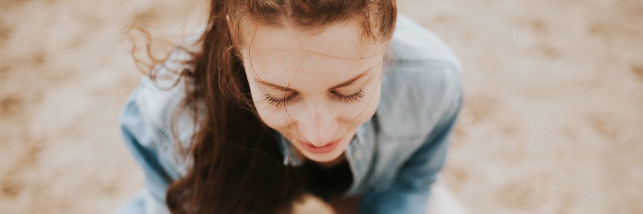 Holding Onto My Enthusiasm and Optimism Through Chronic Illness woman wearing sunglasses on her head and sitting cross-legged outside