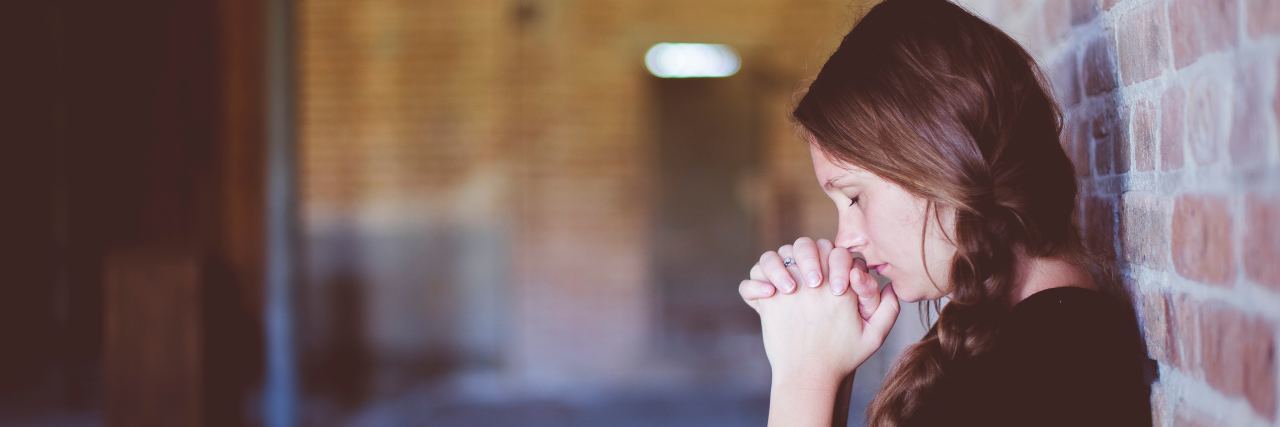 Why New Treatments for My Rheumatoid Arthritis Give Me Anxiety A girl leaning against a brick wall, looking overwhelmed.