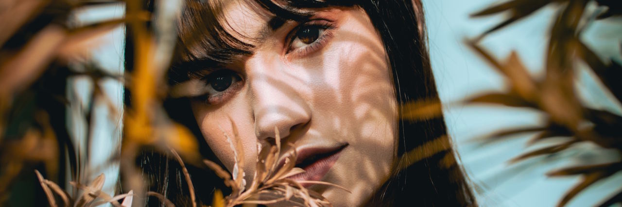 7 Ways to Ground Yourself When Emotionally 'Numb' or Dissociated woman posing behind tree branches