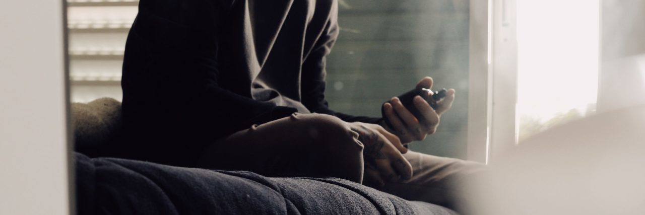 How Depression Is Nothing Like the Movies man sitting on bed holding bottle of aftershave or cologne