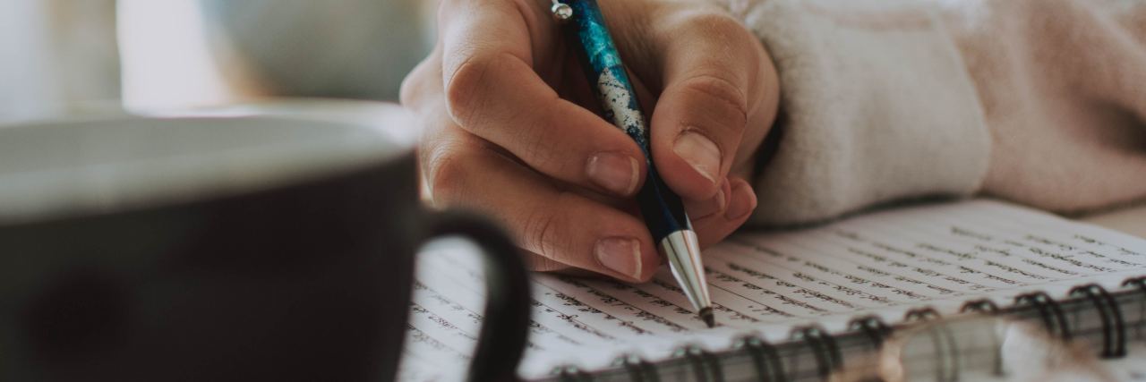 Using Mood Chart to Track Bipolar Disorder journaling woman writing in notebook with mug of coffee