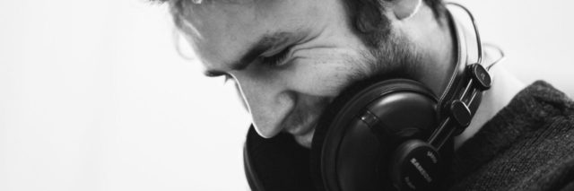 black and white photo of man smiling wearing headphones