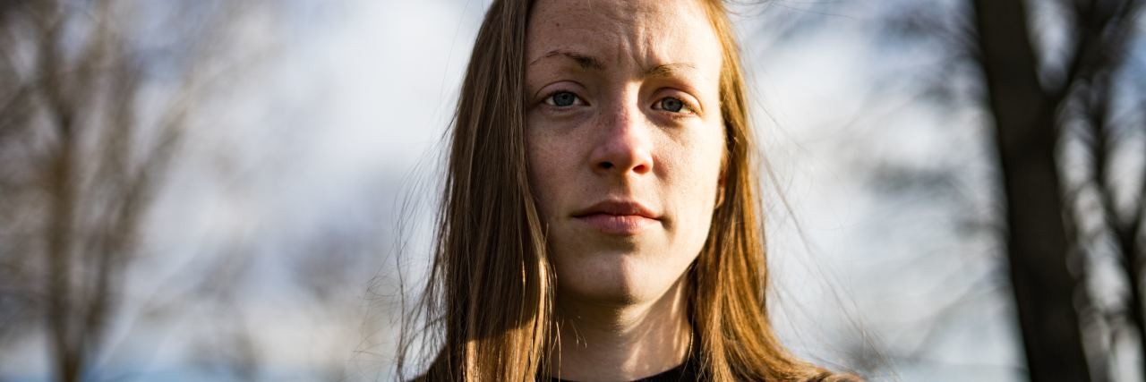 Not Being Able to Plan Ahead or Be Spontaneous With Fibromyalgia blonde woman standing outside under trees frowning
