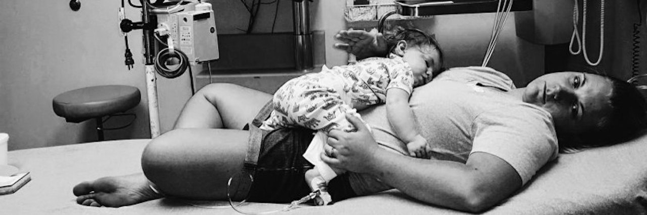 This Is What Being a 'Medical Mama' Means Black and white image of mom with child laying on her at the hospital.