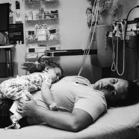 Black and white image of mom with child laying on her at the hospital.
