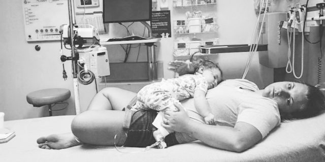 Black and white image of mom with child laying on her at the hospital.