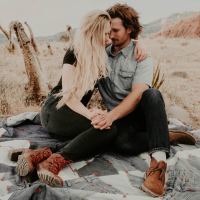 couple sitting on rock in middle of desert holding each other