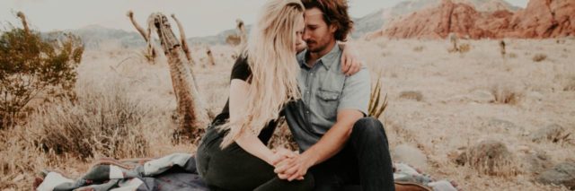 couple sitting on rock in middle of desert holding each other