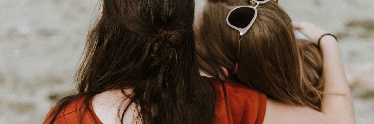 How to Start Talking to a Friend About Suicide two women holding each other by seaside facing away from camera