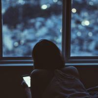 photo of woman taken at night lying on bed with smartphone in hand