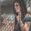 woman with dark hair holding on to chainlink fence
