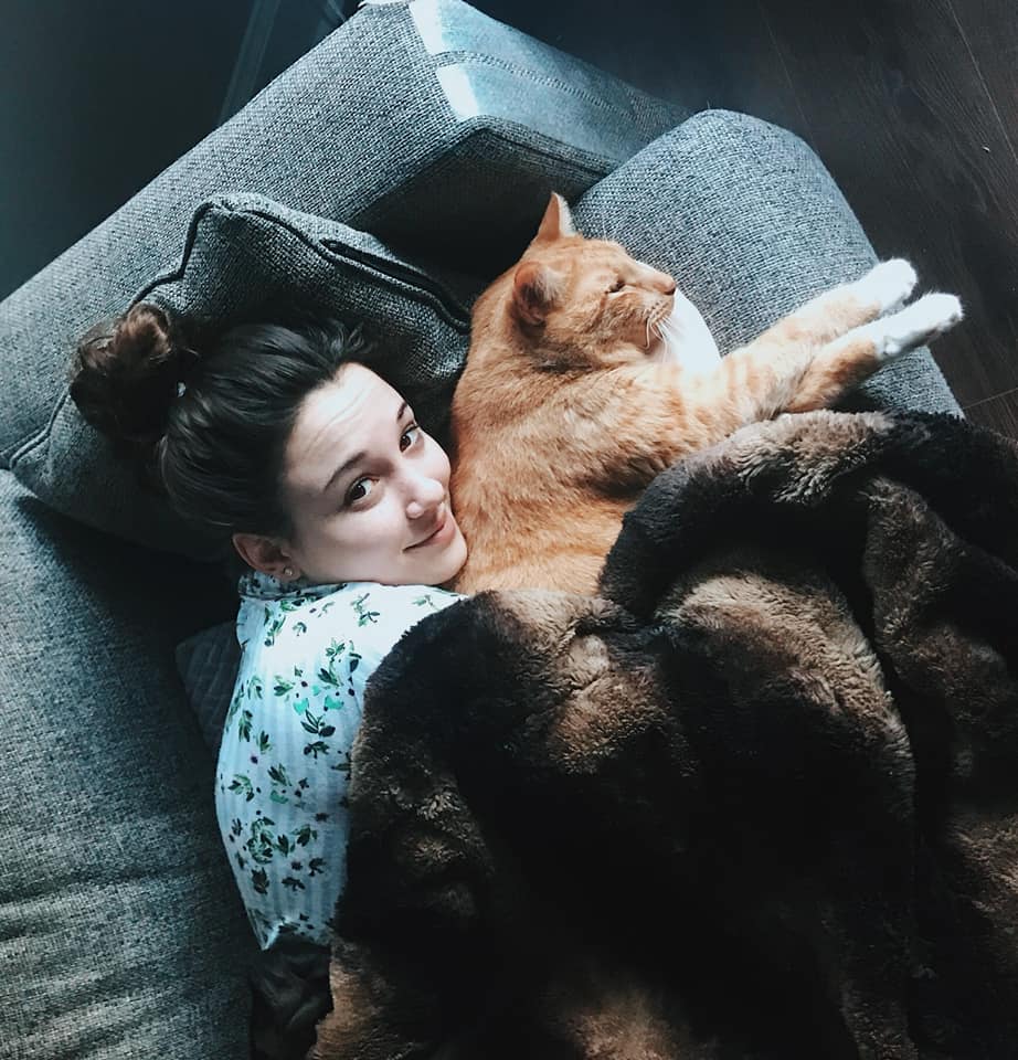 woman lying on the couch with her orange cat