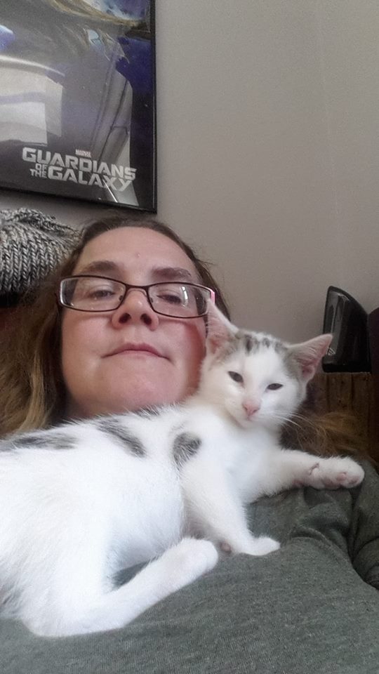 woman sitting on the couch with a cat lying across her chest