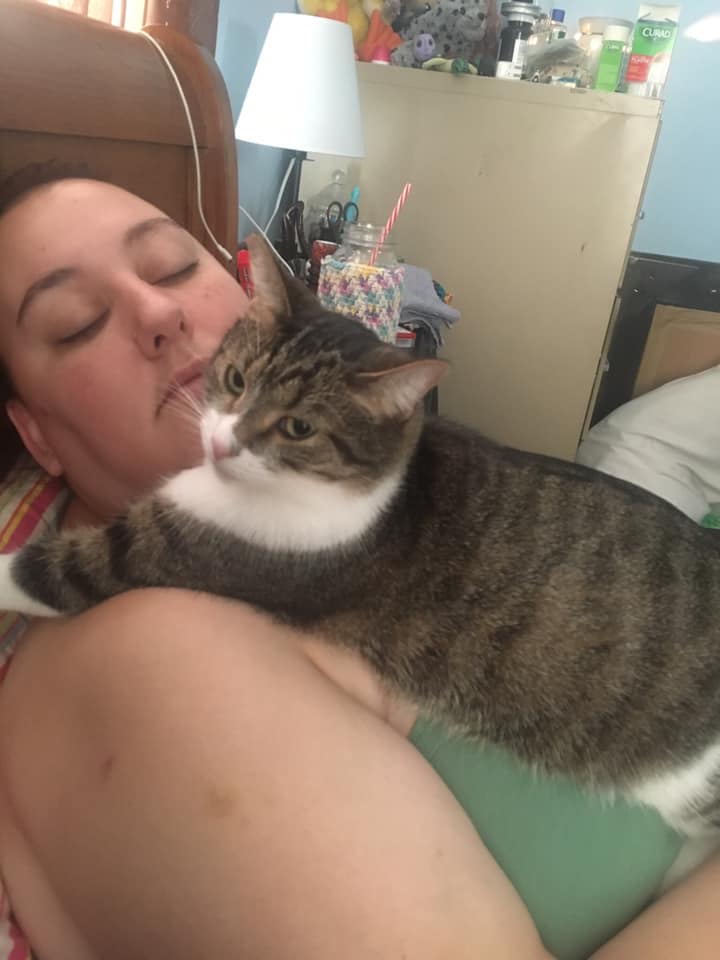 woman lying down with a cat on her chest
