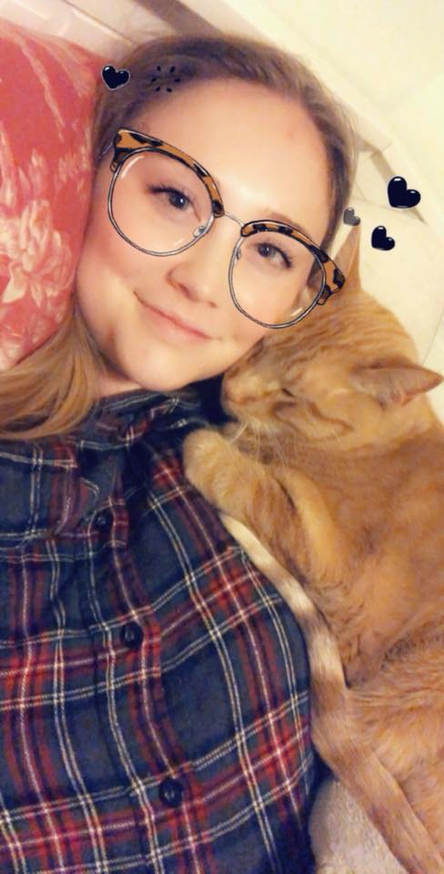 woman wearing a plaid shirt and lying with her orange cat