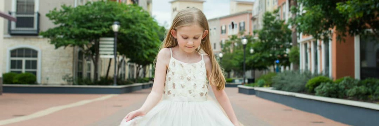 Callie in a pretty white dress. Her prosthetic leg is visible.