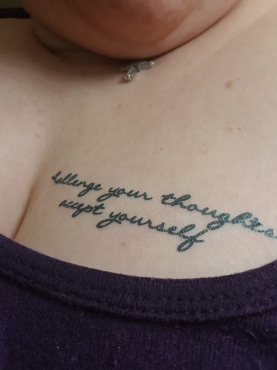 A woman with the words challenge your thoughts accept yourself tattooed on her chest