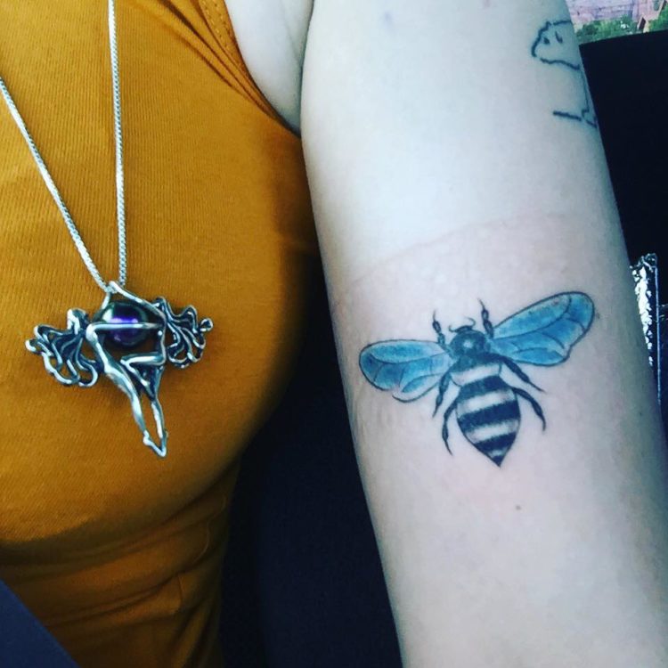 A woman with a bee tattoos on her forearm