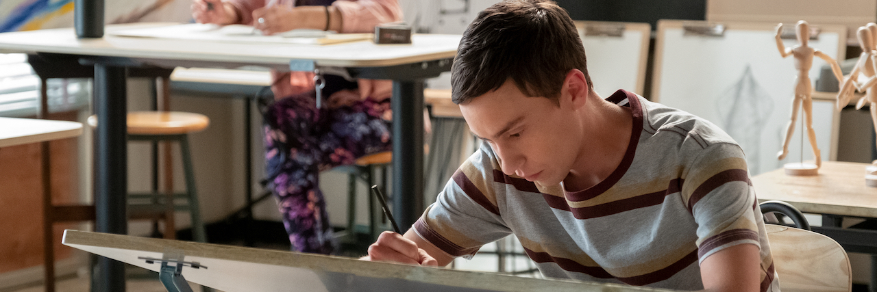 Atypical's Sam bent over a desk working