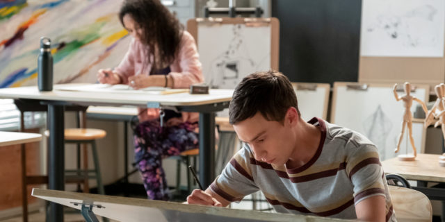 Atypical's Sam bent over a desk working