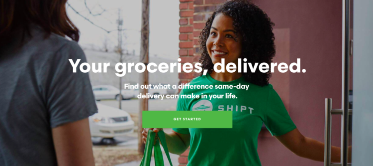 Picture of a woman with curly hair delivering groceries and smiling. 