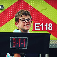 Gavin McHugh poses with a fire truck on the set of the TV show 911.