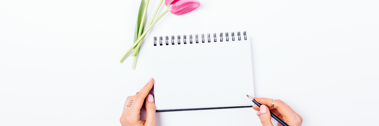 7 Gifts to Give Someone Who Is Struggling Right Now a female's hands writing a note with a fresh pink bouquet