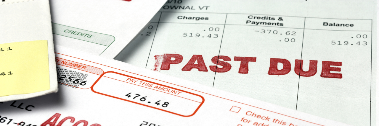 The Fear of Losing Disability Benefits A stack of past due bill notices.