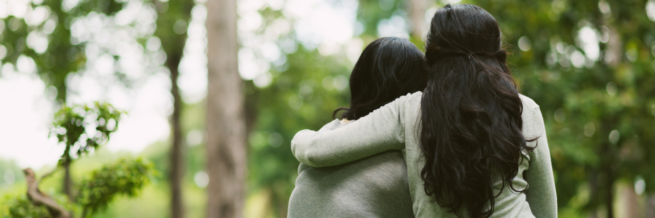 10 Ways to Be a Better Friend to Someone With Chronic Illness Rear view of hugging female friends sitting in the park