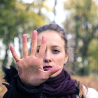 Woman holding her hand up to say "stop" in a forest