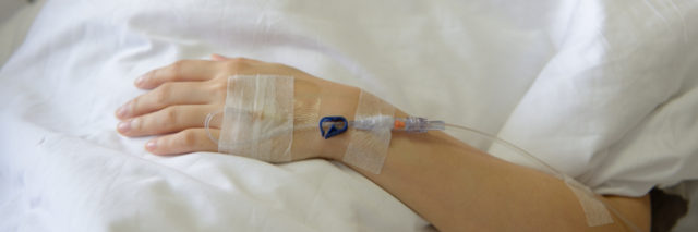A woman laying in a hospital bed with an IV in her arm.