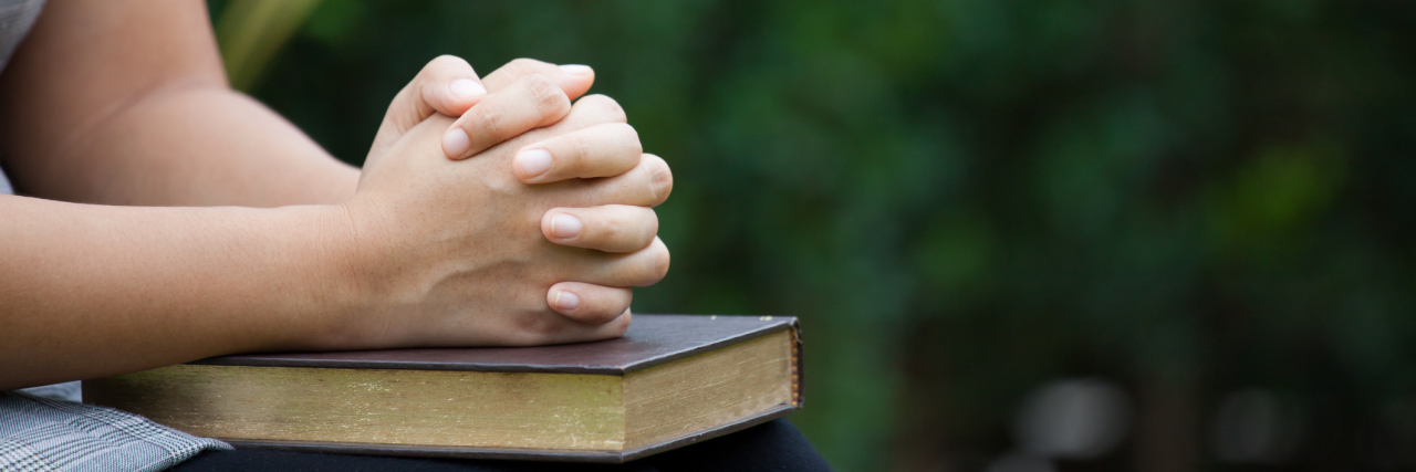 A picture of a woman with her hands folded on top of a Bible.
