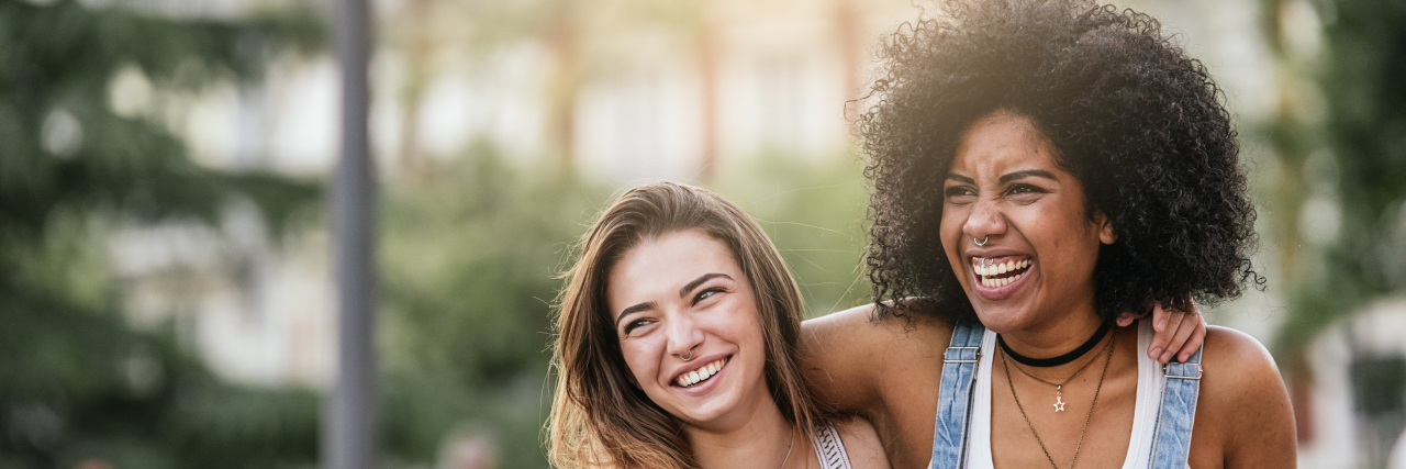 8 Helpful Ways to Offer Support to Loved Ones With Chronic Illness women having fun in the street, smiling, with their arms around each other